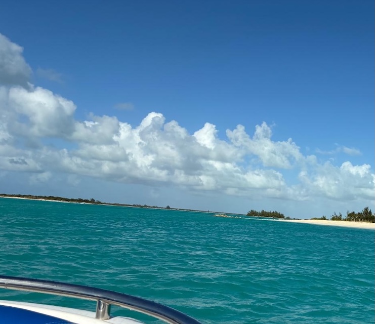 We see the prow of the small boat as it approches the beach in the middle distance of the adjacent island of Pine Cay